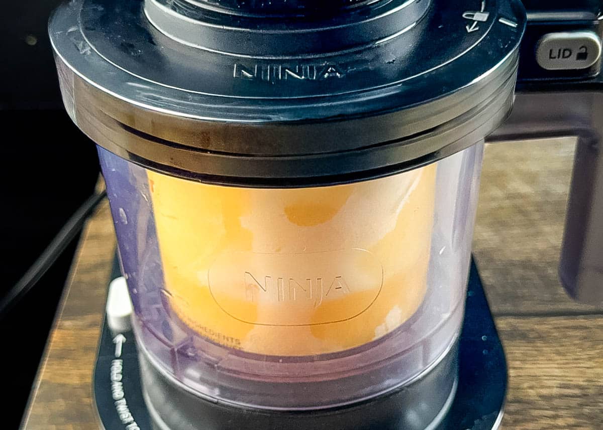 The frozen eggnog base being processed in the Ninja Creami machine.