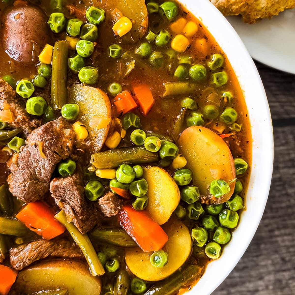 Hearty old fashioned beef vegetable soup served hot in a bowl with chunks of beef and vegetables.