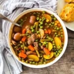 Old-fashioned beef vegetable soup with tender beef, potatoes, carrots, peas, and green beans in a rich broth, served in a white bowl.