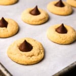Peanut butter blossoms on a parchment paper lined baking sheet, ready to be served.