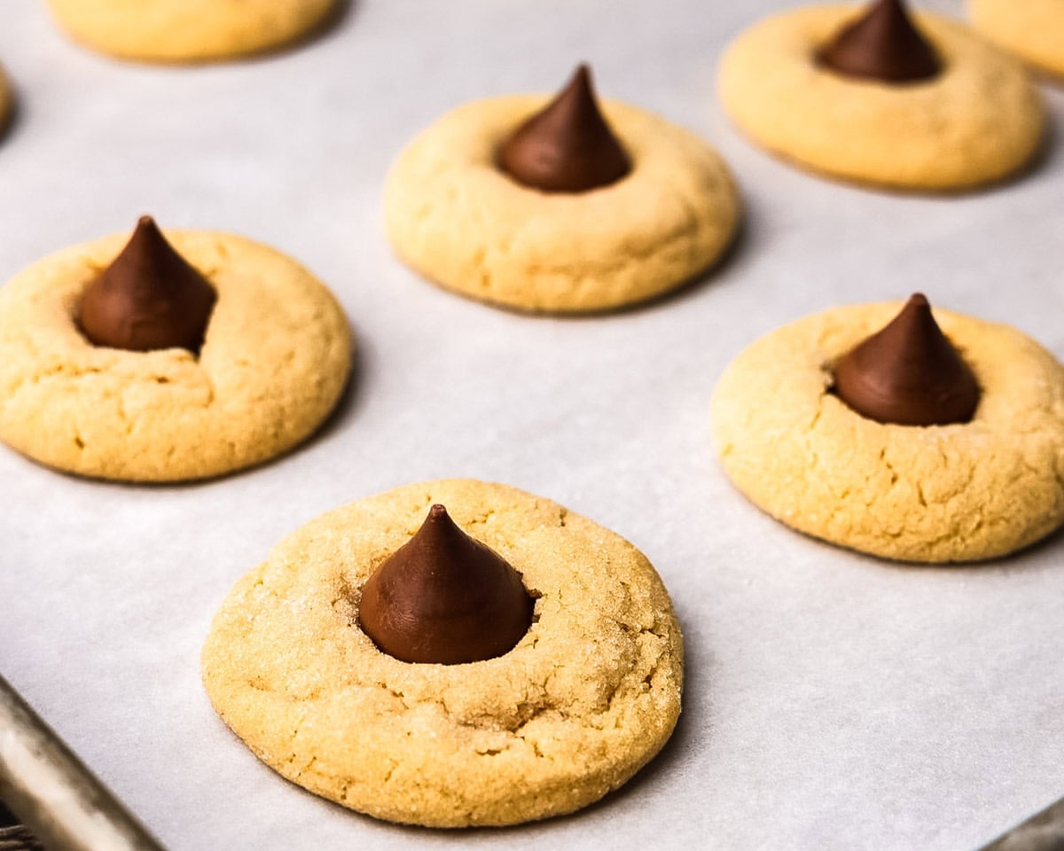 Peanut butter blossoms on a parchment paper lined baking sheet, ready to be served.