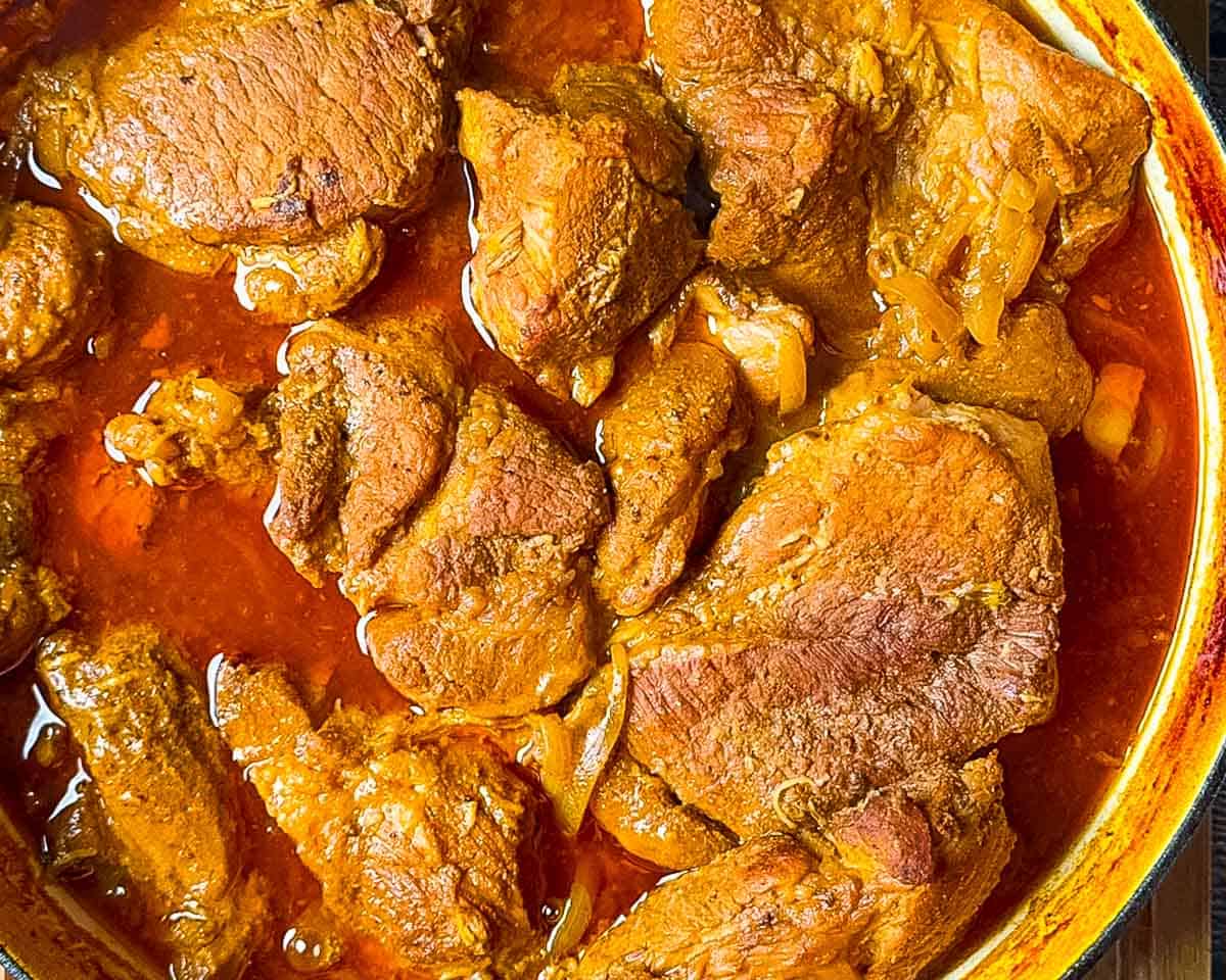 BBQ braised pork shoulder cooking low and slow in a Dutch oven.