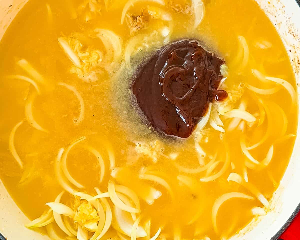 Chicken broth, barbecue sauce, and aromatics combined in a Dutch oven to make braising liquid.