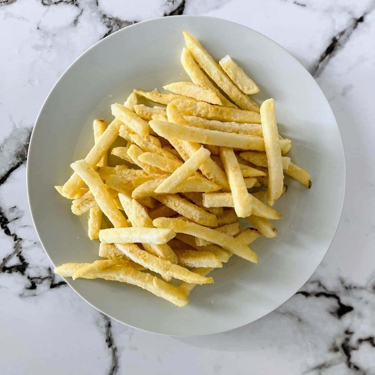 Frozen french fries on a white plate.