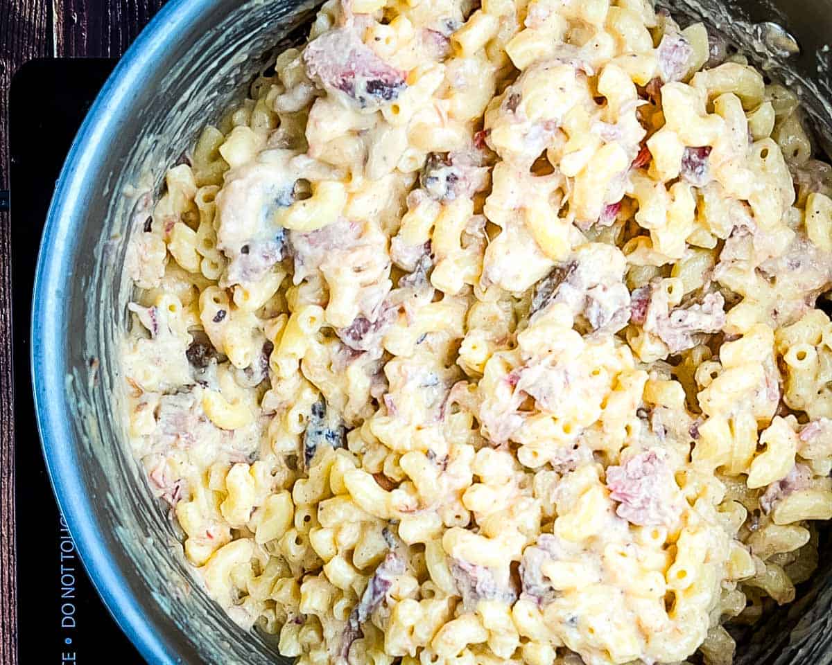 Cooked macaroni stirred into brisket cheese sauce until fully coated.