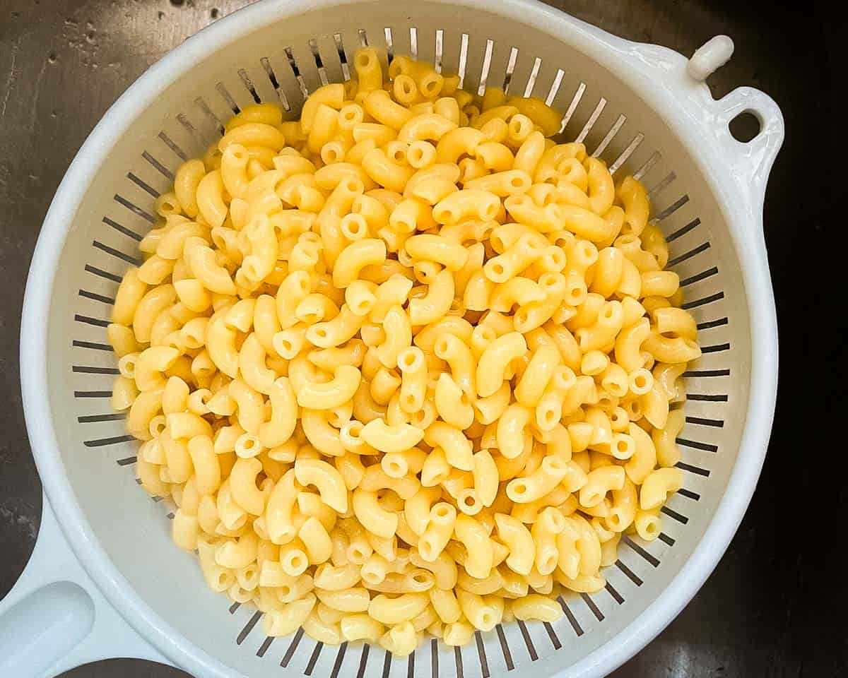 Cooked elbow macaroni drained in a colander after boiling to al dente.