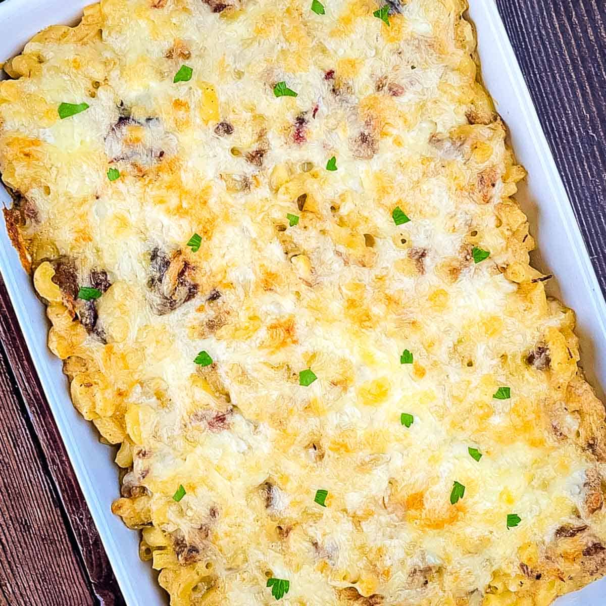 Creamy baked mac and cheese with chopped brisket in a casserole dish.