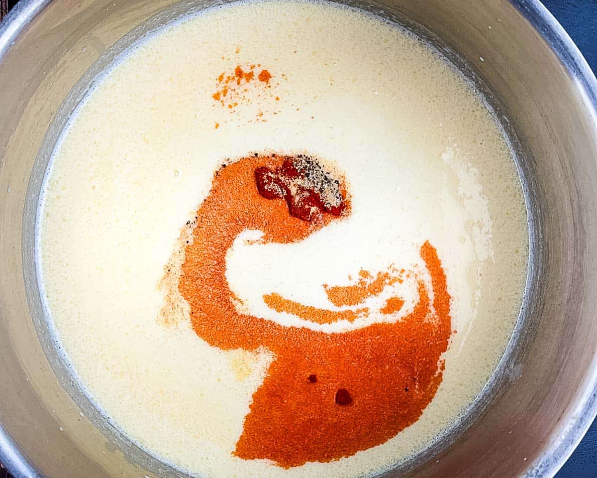 Milk and half-and-half whisked into the roux to start the cheese sauce, with seasonings added.
