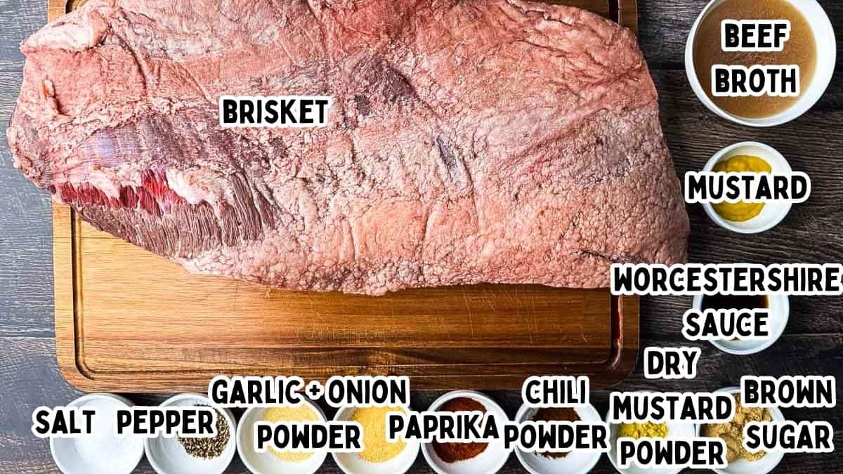Raw whole brisket on a cutting board with dry rub ingredients and braising liquids arranged around it.