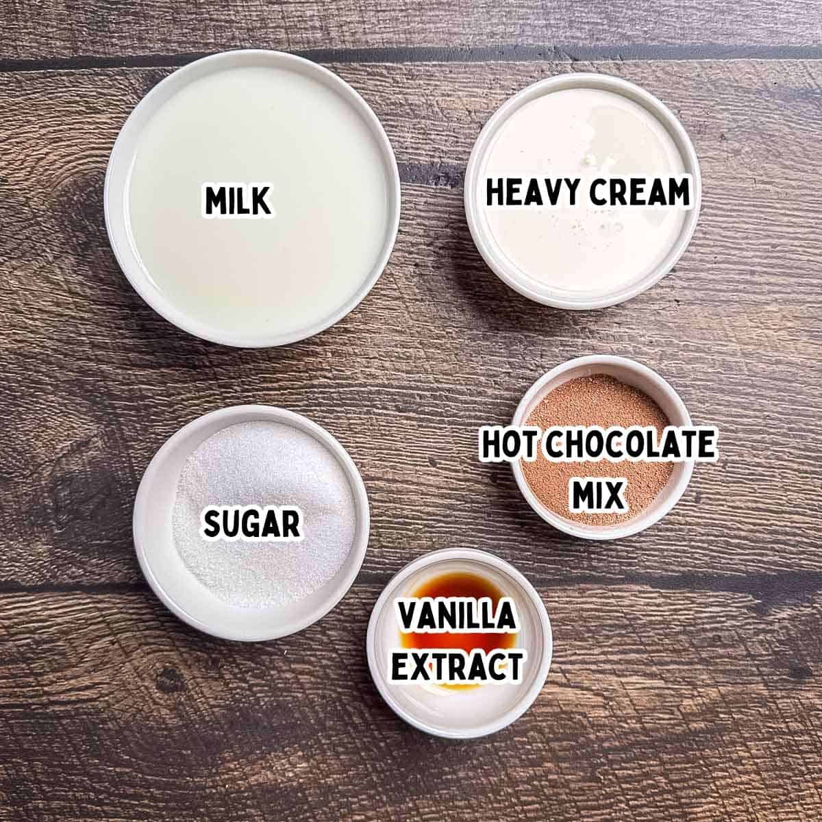 The labeled ingredients for hot chocolate ice cream made in the Ninja Creami in white bowls on a wooden table.