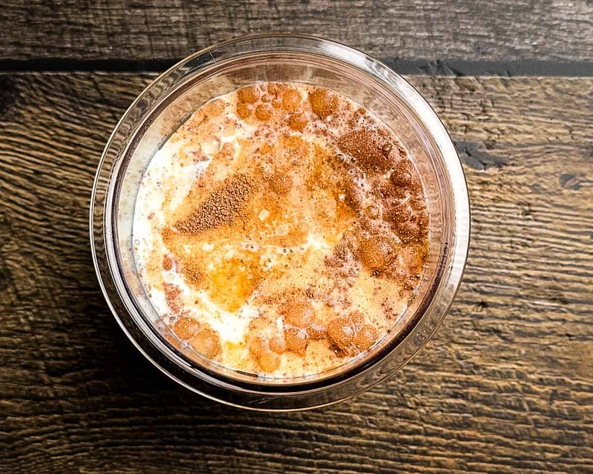 Milk, sugar, hot chocolate mix, and vanilla combined in a Ninja Creami pint container before mixing.