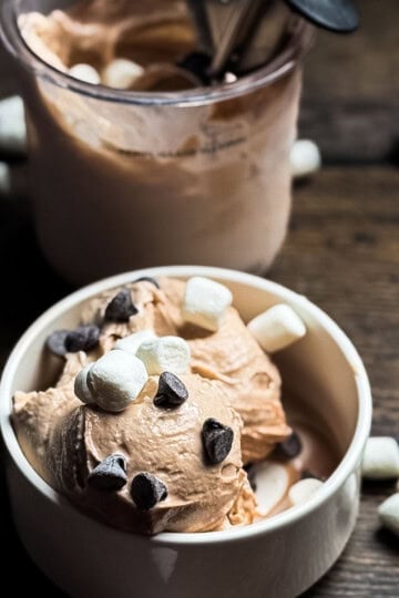 Ninja Creami hot chocolate ice cream topped with mini marshmallows and chocolate chips in a white bowl.
