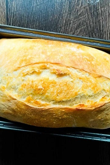 No knead sourdough sandwich bread baked in a loaf pan with a soft, fluffy crumb and golden crust.