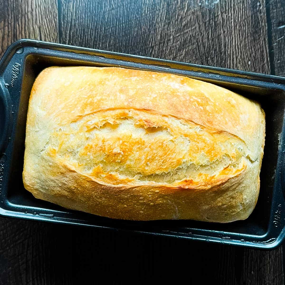No knead sourdough sandwich bread baked in a loaf pan with a soft, fluffy crumb and golden crust.