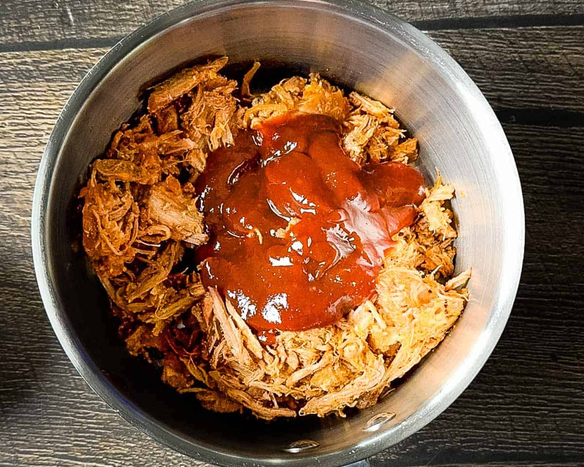 Warming leftover pulled pork and barbecue sauce in a saucepan.