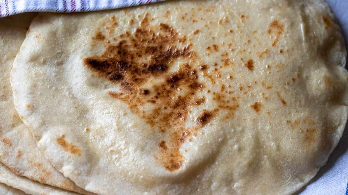 Rustic sourdough flatbread cooked in a skillet with browned spots and soft, chewy texture.