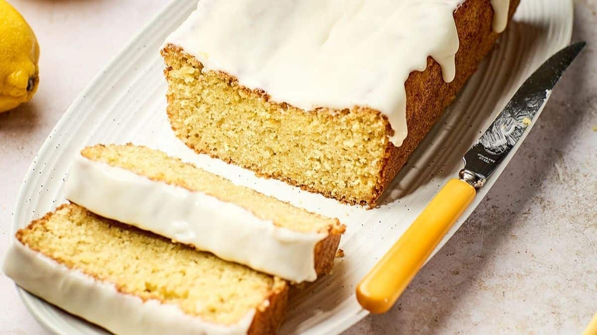 Sourdough lemon loaf cake with glaze, sliced to show tender crumb on a serving plate.