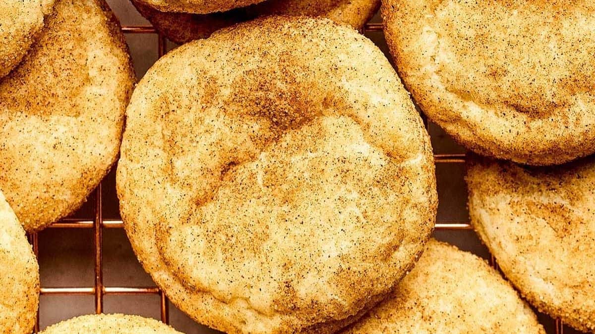 Sourdough snickerdoodle cookies coated in cinnamon sugar cooling on a wire rack.