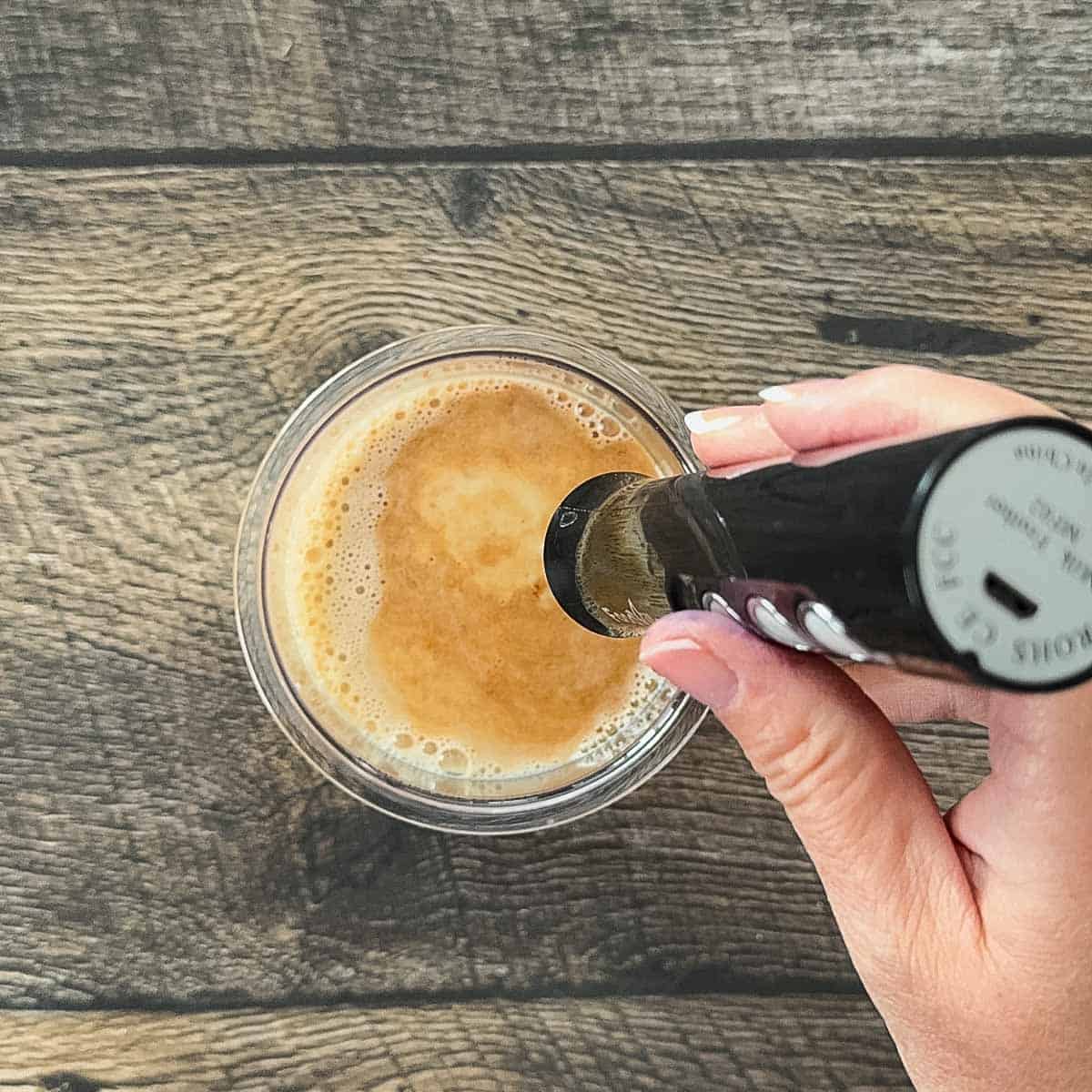 Using handheld frother to mix chai ice cream base in Ninja Creami pint.