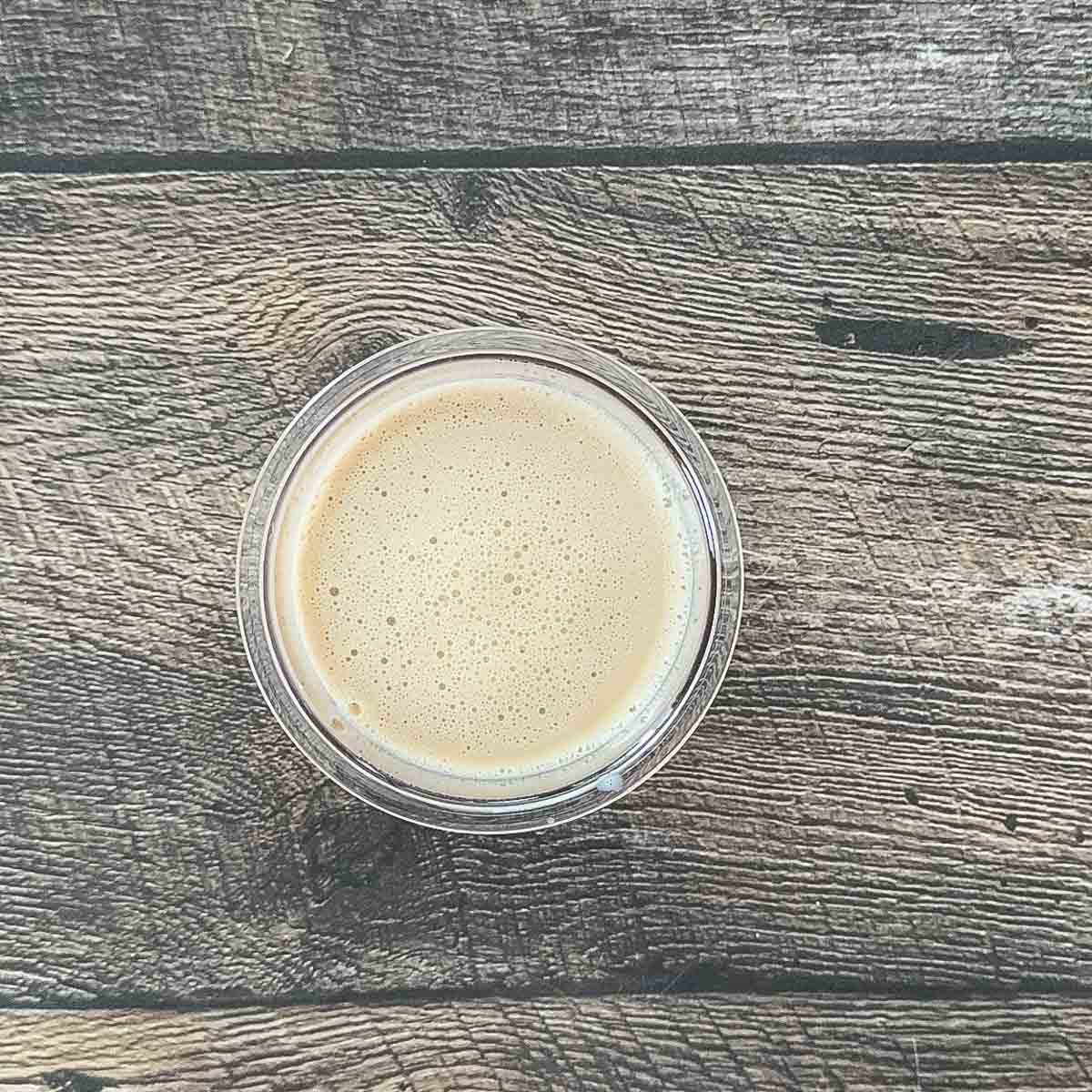 Smooth chai ice cream mixture in Ninja Creami container ready to freeze.