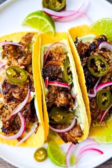 Carnitas street tacos with tender pulled pork, jalapeño slices, red onions, and avocado lime crema on corn tortillas.