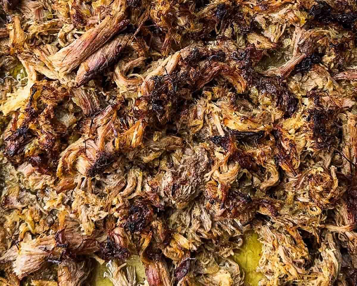 The crispy shredded pork on a baking sheet after being broiled.