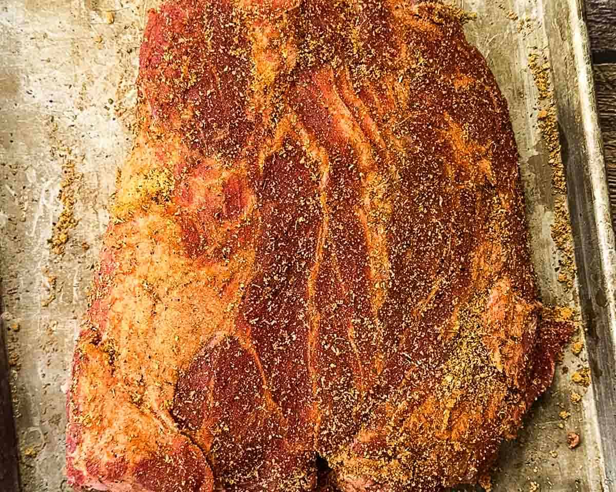 The pork shoulder covered in spice rub.