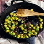 Smoked Brussels sprouts with bacon cooked in a cast iron skillet on a pellet grill.