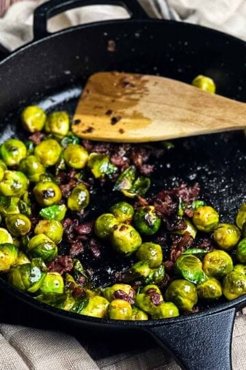 Smoked Brussels sprouts with bacon cooked in a cast iron skillet on a pellet grill.
