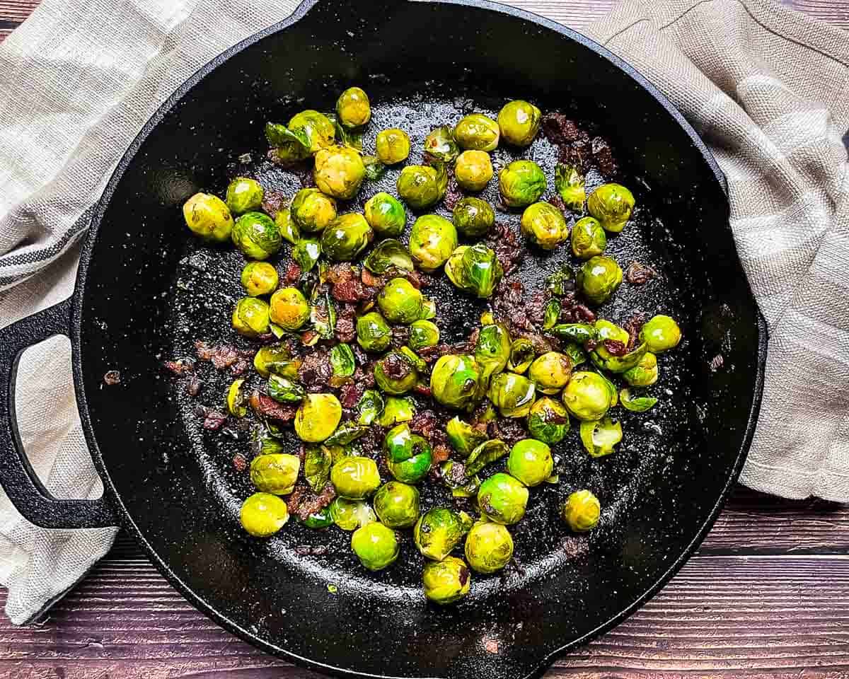 Brussels sprouts with bacon in a skillet showing crispy edges.