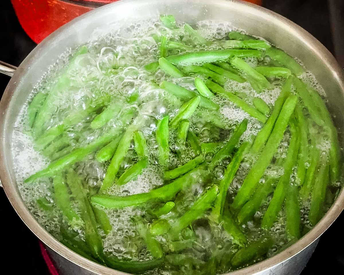 Fresh green beans being blanched in a Dutch oven.