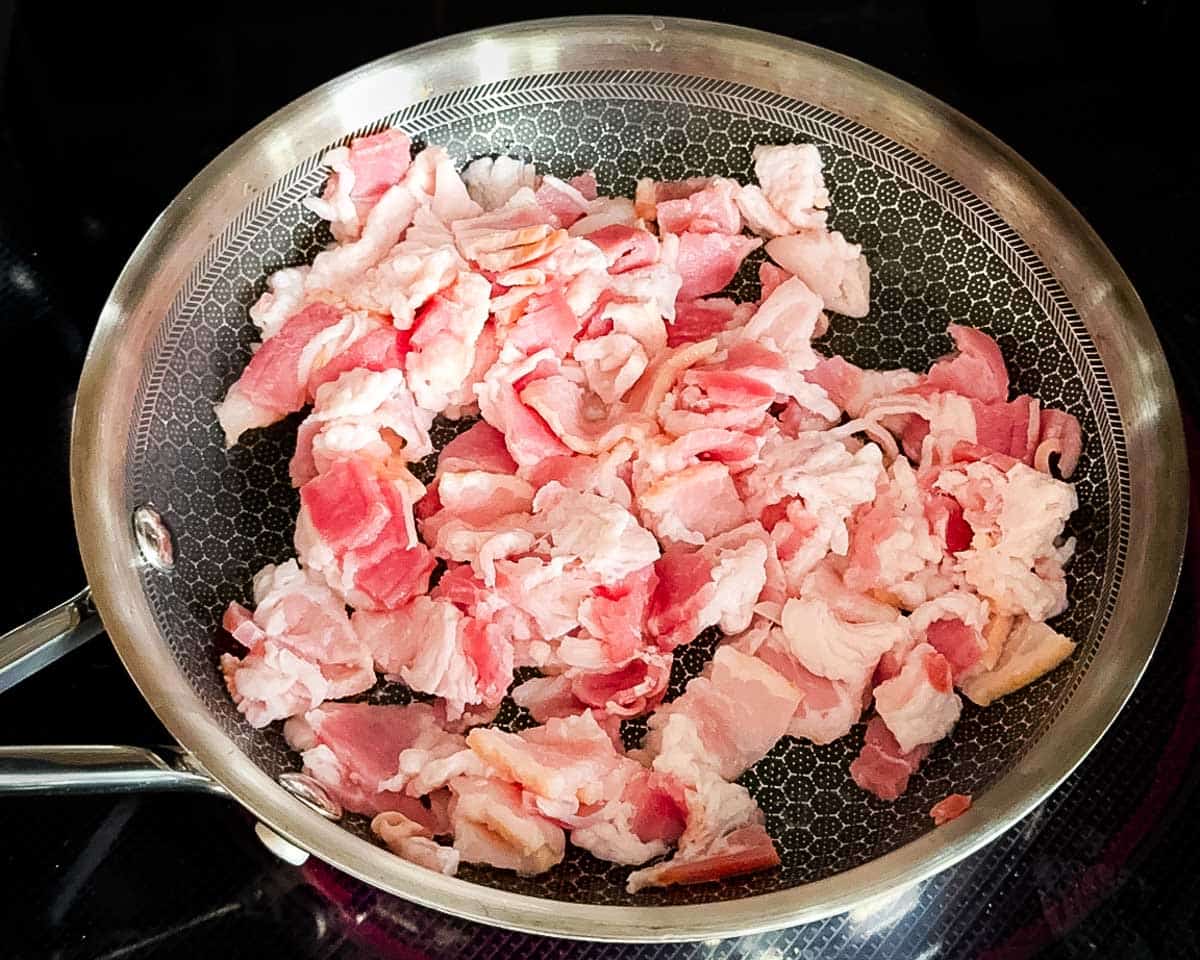 The diced bacon in a cast iron skillet.