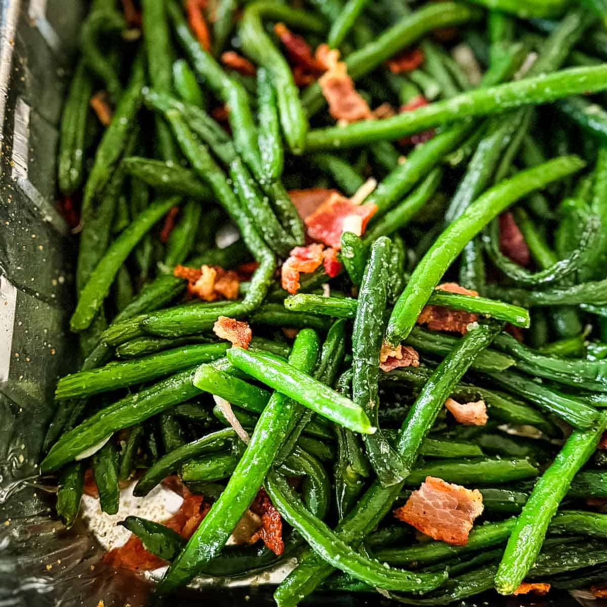 Green beans with bacon and onion in a foil pan just removed from the pellet smoker.
