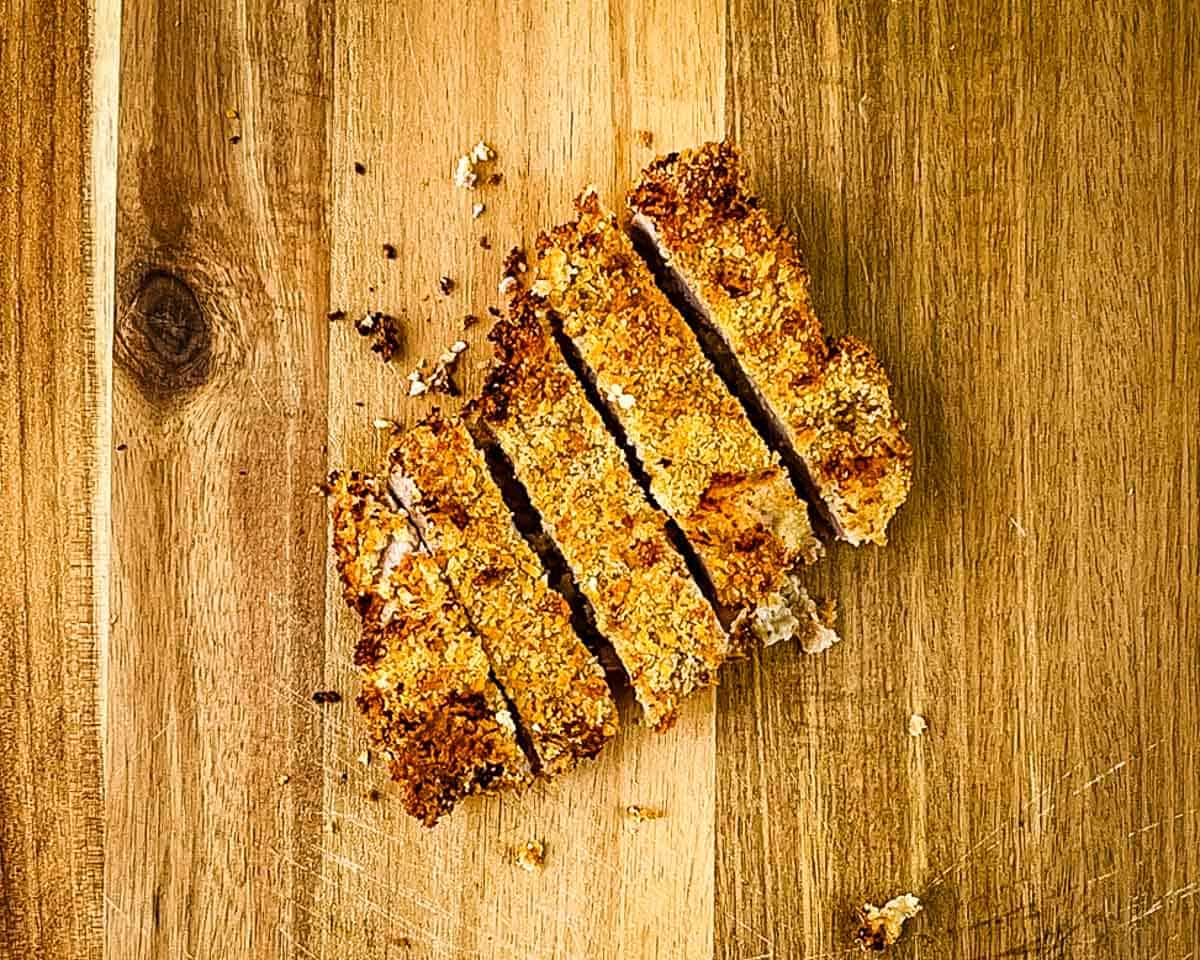 Sliced air fryer pork tonkatsu on a cutting board showing crispy coating and juicy inside.