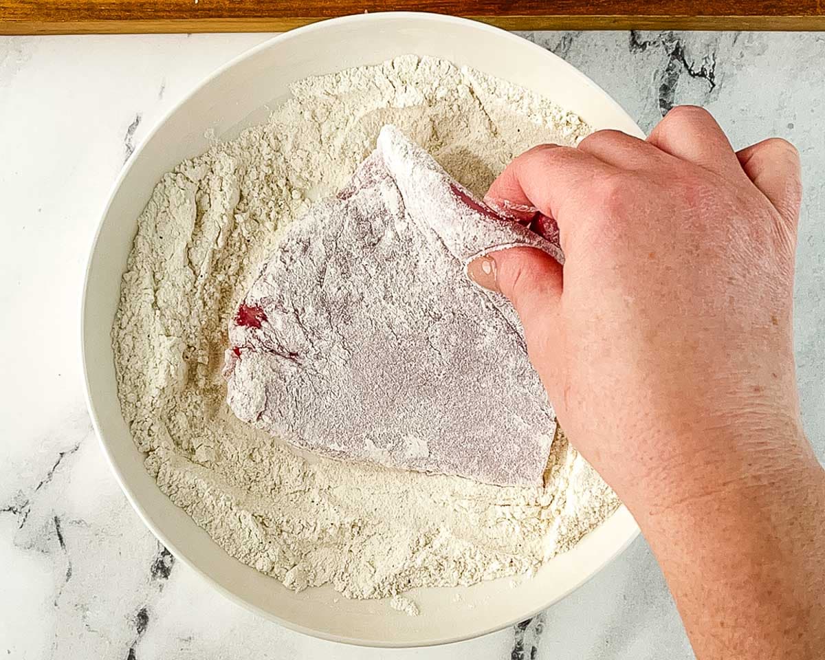 Pork cutlet coated in seasoned flour as the first step of dredging for tonkatsu.