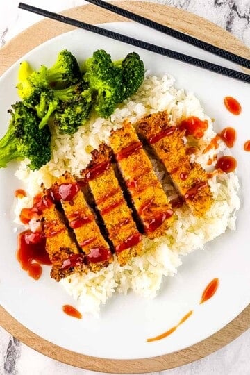 Air fryer pork tonkatsu sliced over white rice with broccoli and drizzled with tangy tonkatsu sauce.
