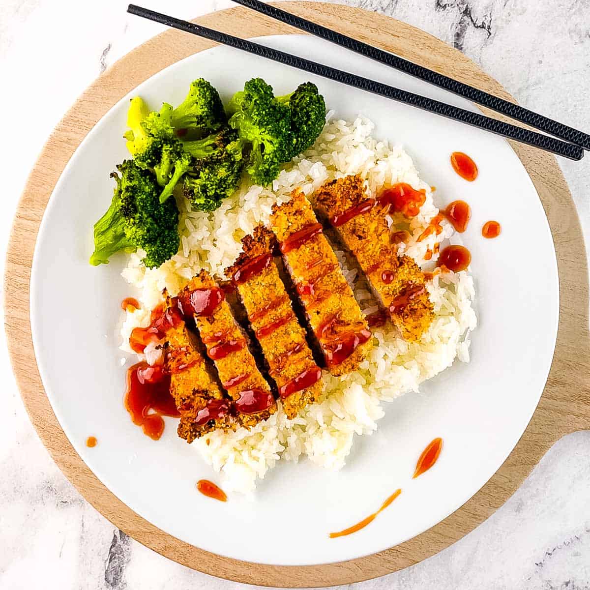 Air fryer pork tonkatsu sliced over white rice with broccoli and drizzled with tangy tonkatsu sauce.