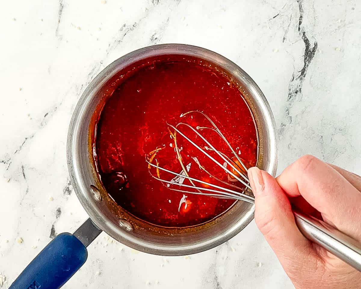Whisking tonkatsu sauce ingredients in a small saucepan until smooth.