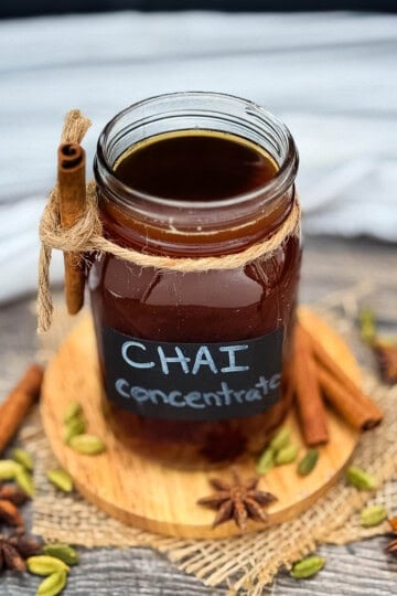 Homemade chai tea concentrate in a mason jar with cinnamon sticks, cardamom, and whole spices.