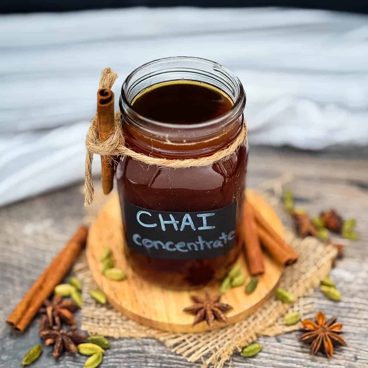 Homemade chai tea concentrate in a mason jar with cinnamon sticks, cardamom, and whole spices.