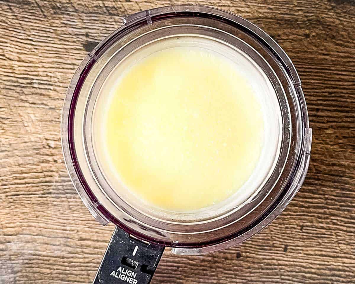 The frozen vanilla yogurt pint placed inside the Ninja Creami outer bowl assembly.