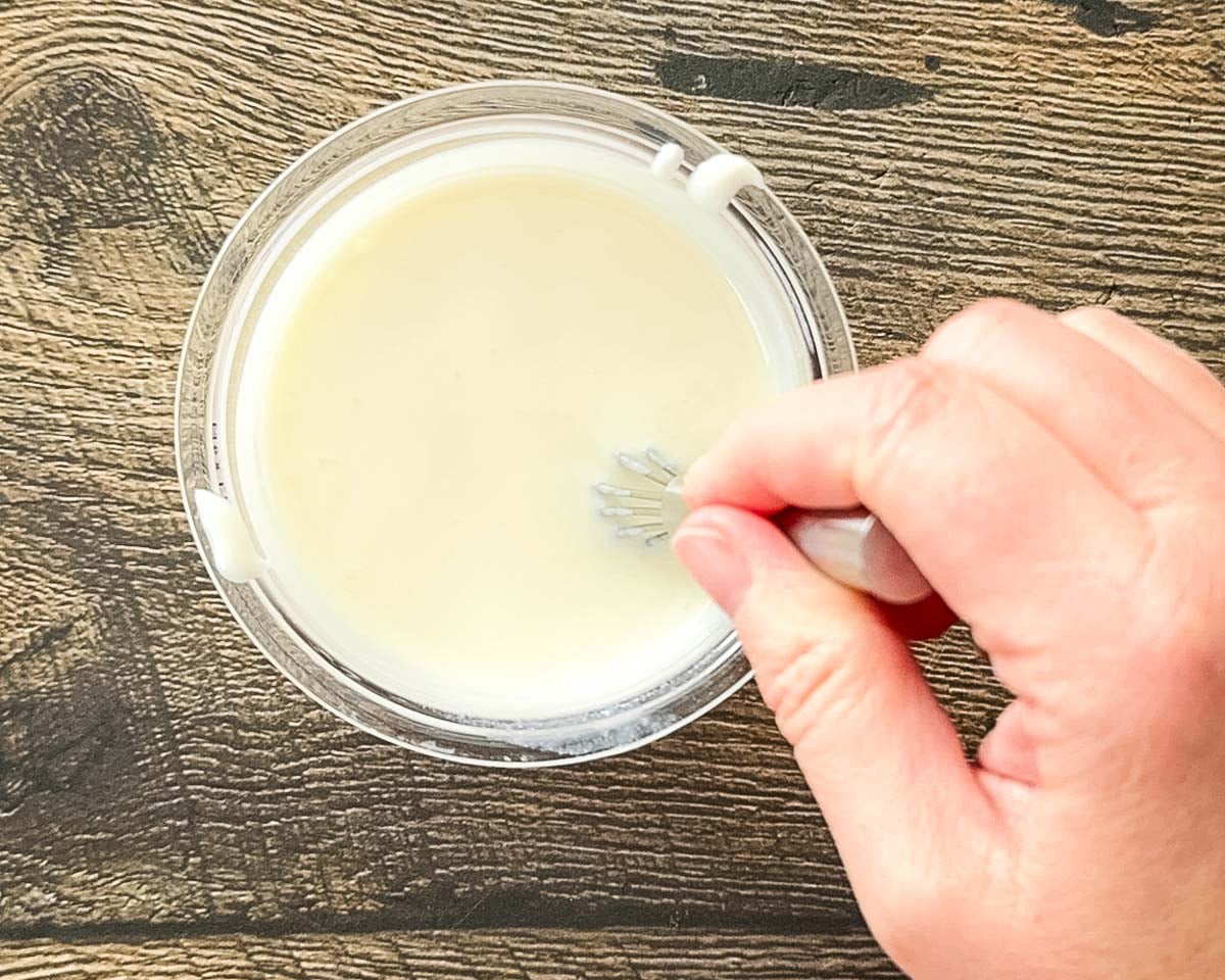 Whisking the yogurt and milk in a Ninja Creami pint container.