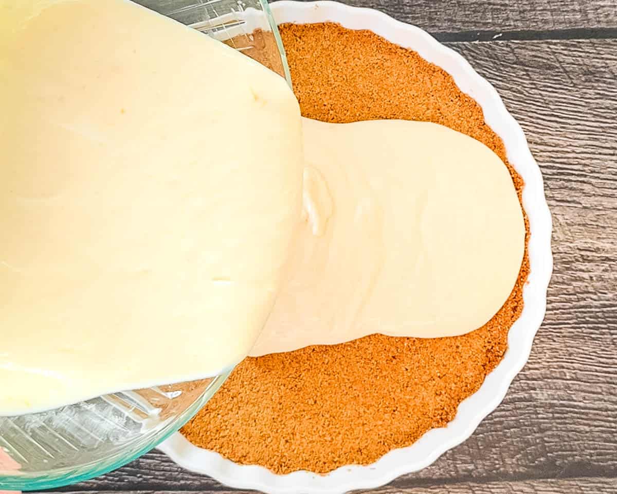 The lemon cream filling being poured into the graham cracker crust.