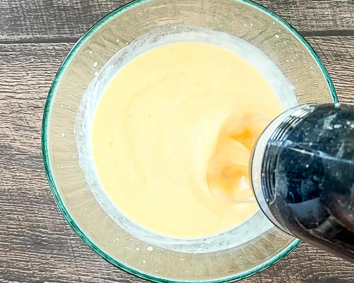 Mixing together fresh lemon juice and sweetened condensed milk in a glass bowl to create the citrus base for the pie.