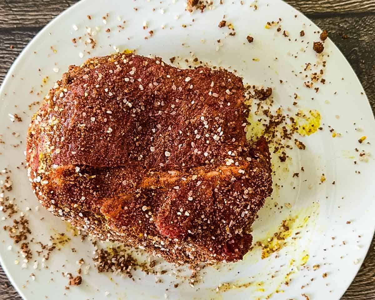 Seasoned beef roast on a white plate.