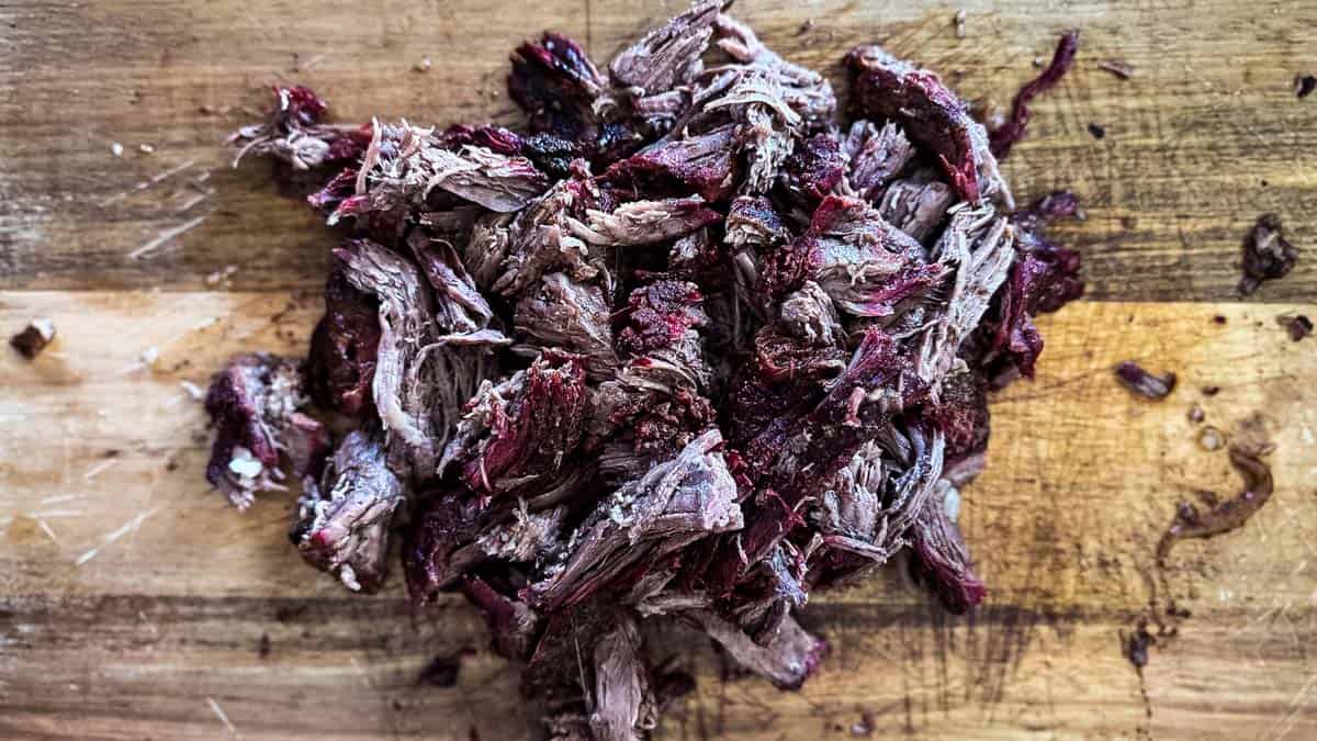 Smoked shredded beef piled on cutting board with crispy bark edges.