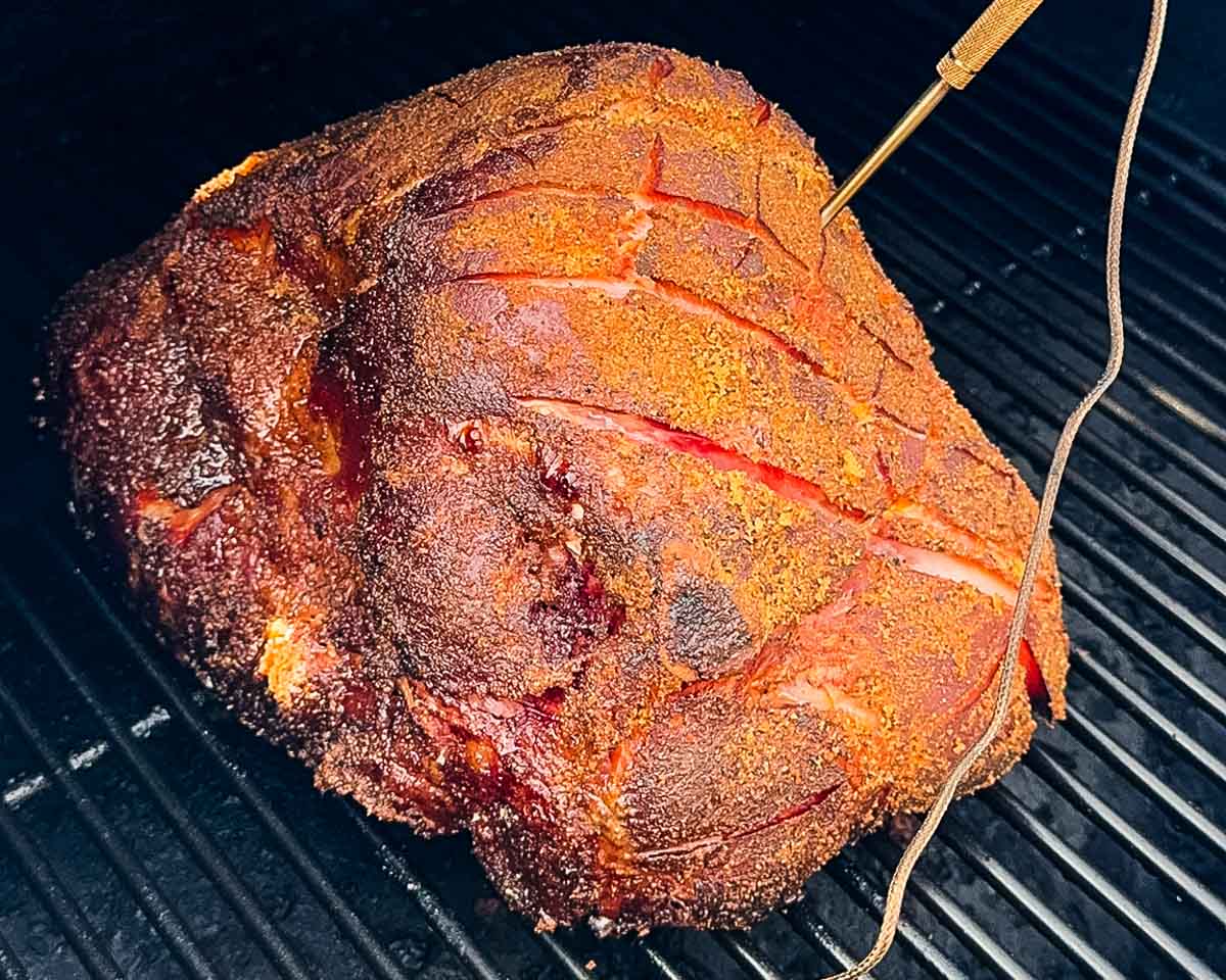 Ham on pellet grill with temperature probe inserted.