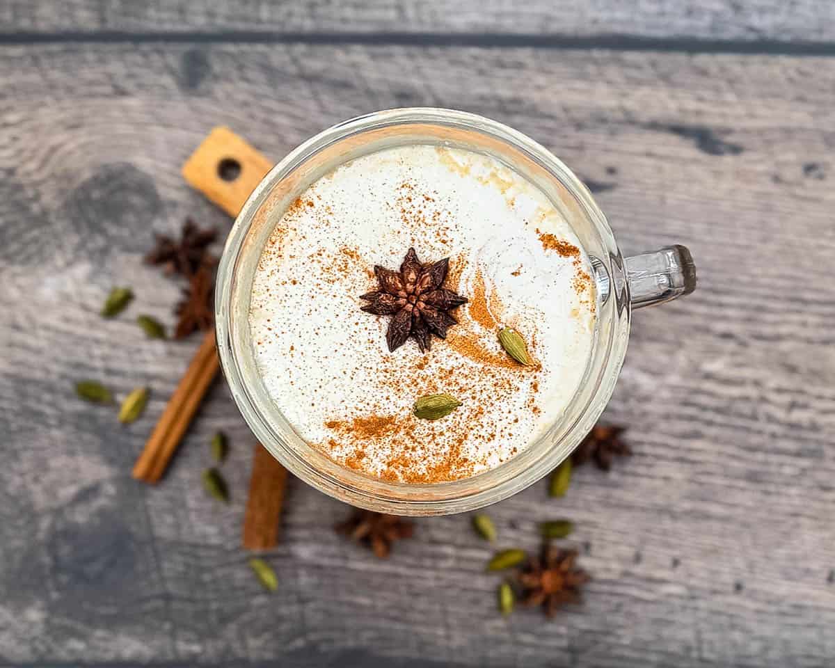 Hot chai tea latte with foam and cinnamon garnish in mug.
