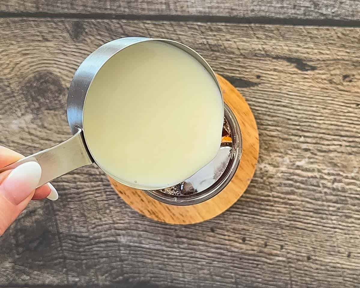 Adding milk to chai tea over ice for iced latte.