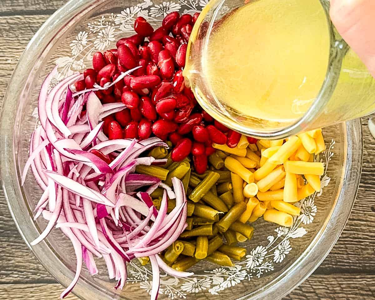 The dressing being poured over the beans and red onion.